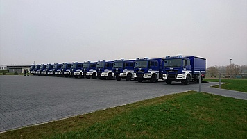 Eine Serie fabrikneuer THW-LKWs, auf einem Parkplatz in Reihe aufgestellt